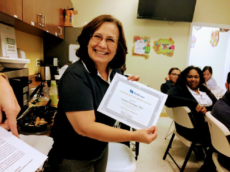 Dr. Portugal smiling and holding up her certificate of completion from the Patient Care Advocacy program.
